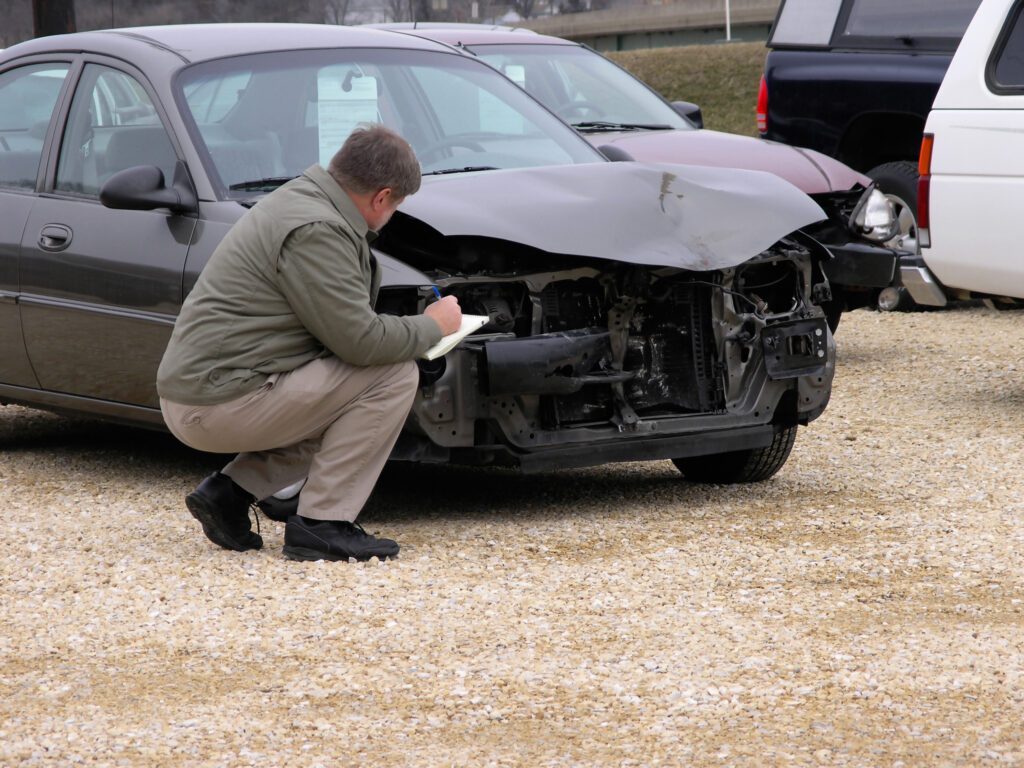 Insurance claim adjuster Inspecting Damaged Car.