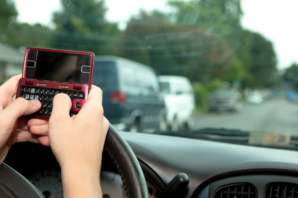 An unsafe driver texting while driving.